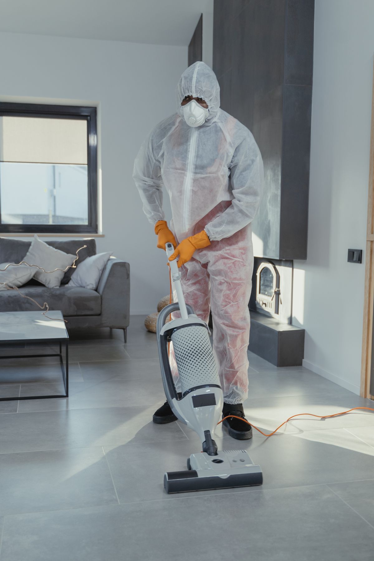 Cleaner in protective equipment vacuuming in a modern commercial space